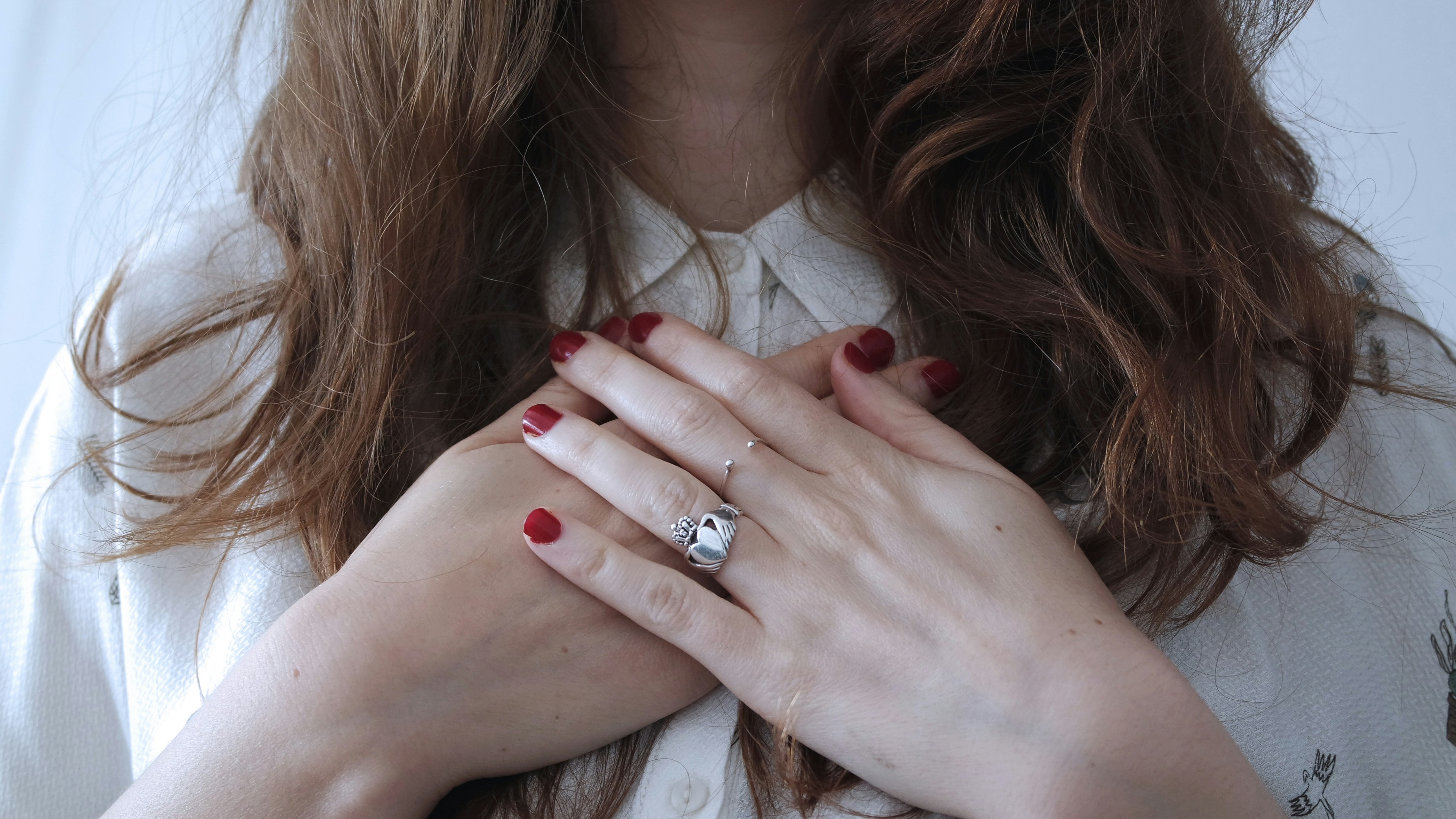 A woman resting both hands over her heart, a gentler, more curious way to understand what she is feeling