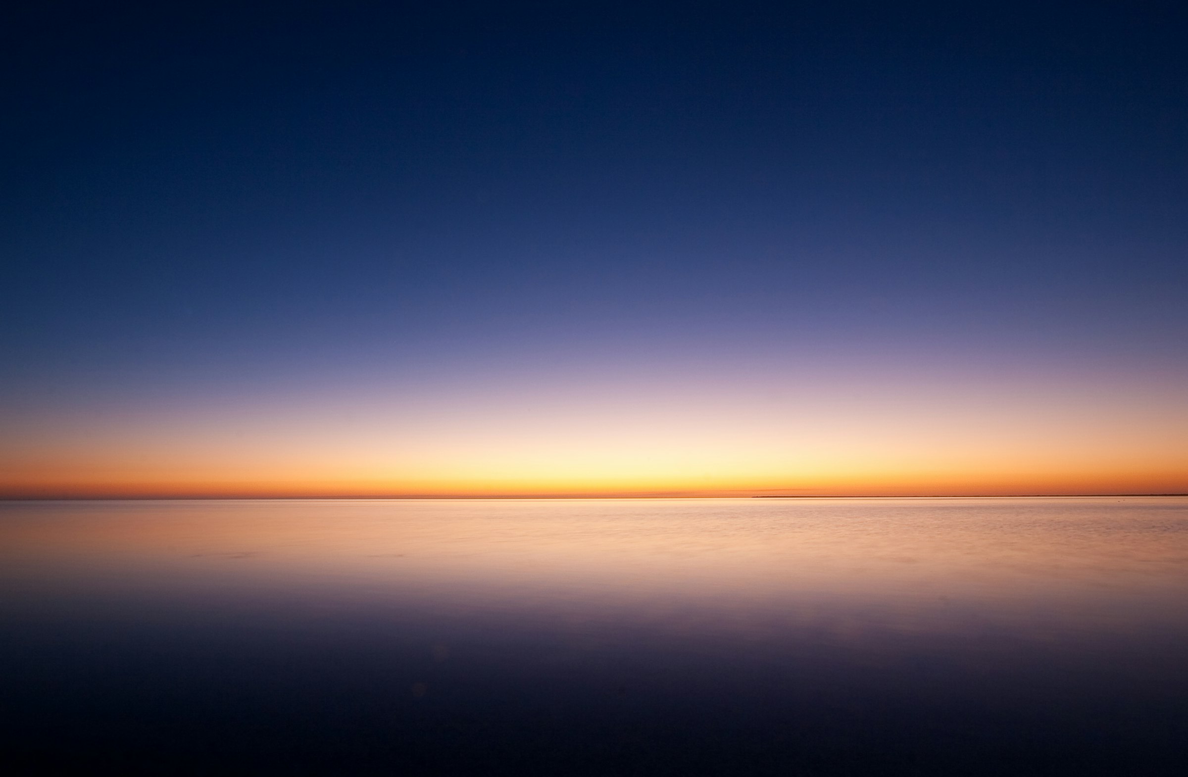 Calm ocean at dusk with a soft glow on the horizon