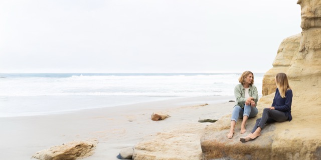 Two women sitting together on the beach — connection and support